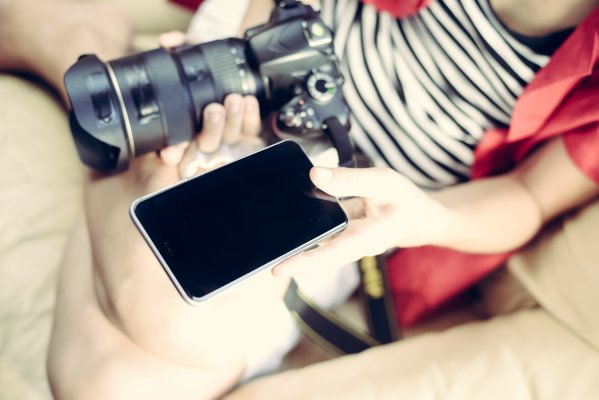 girl holding smartphone and dslr camera